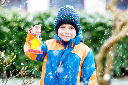 Plakat Małe dziecko chłopiec obwieszenia ptaka dom na drzewie dla karmić w zimie