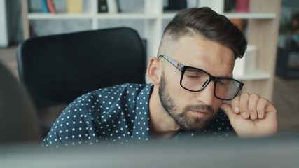 Close up portrait young attractive man office software engineer developer it programmer technical learning serious glasses looks at monitor screen freelance solves engineering problems. Slow motion