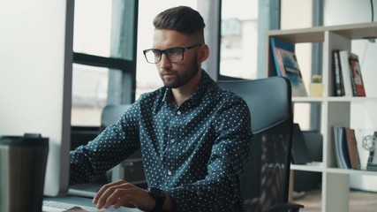 Portrait of young attractive man use computer in office, software engineer developer it programmer, technical learning serious in glasses looks monitor screen freelance solves engineering problems.