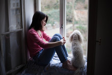 Beautiful Woman And Her White Dog Sitting On The Window