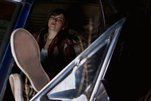 Teenager Leans Back In Front Seat Of Old Car On Dark Night