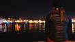 Frau sitzt am Wasser / See in der Nacht / Lichter