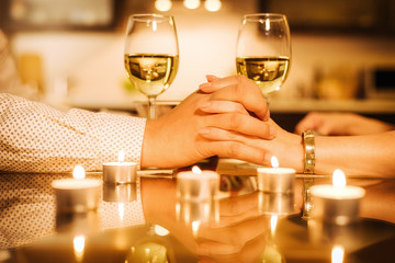 Couple drinking wine and holding hands.