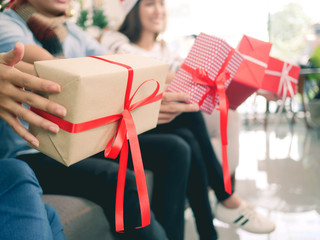 happy group of friends party christmas exchange gift box, close-up man and girl hands holding gift box.