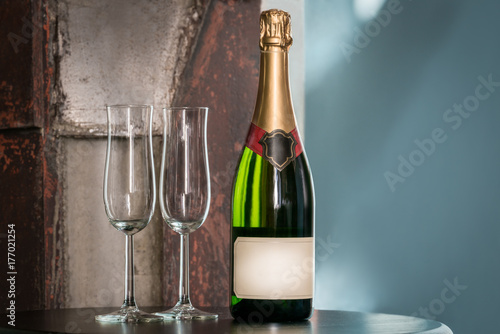 Plakat Indoors wciąż życie strzał nieotwarta szampańska butelka i dwa pustego szkła na stole. Etykieta z miejsca na kopię.