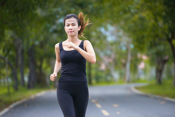 Wall Mural - Young fitness sport woman running on the road in the morning, Sun light flare , Selective focus.