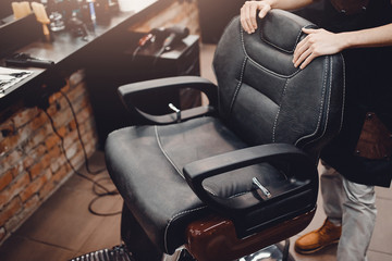 Barbershop. Armchair for hair cutting, hands of hairdresser in barber shop interior