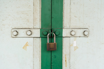 Closed up on vintage white and green wood door with silver lock.