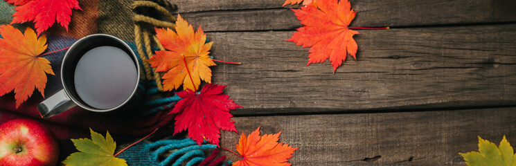 Autumn leaves, two cups of wine, red apples with plaid on old vintage wooden background.