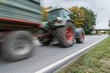 © stgrafix - Vorbeifahrender Traktor auf einer Landstraße, Deutschland