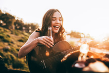 Young Adult Woman Enjoying Beer And Playing Guitar