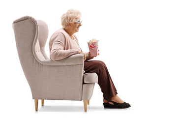 Poster - Mature woman with popcorn and 3D glasses seated in an armchair