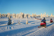 Group of tourists riding snowmobiles in a snowy winter landscape in Lapland, near Saariselka, Finland. Winter holiday sports and adventure in Scandinavia
