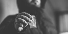 Drug Dealer Selling Drugs Junkie. Drug Abuse Concept And Overdose Concept. Mans Hand Holds Plastic Packet With Cocaine Powder