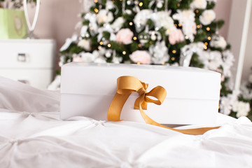 Beautiful luxury gift box with ribbon on bed.