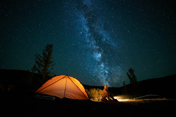 man tourist near his camp tent at night.