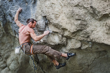 Muscular Man Rock Climbing A Difficult Route