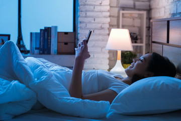 Asian women are using the smart phone on the bed before she sleeping at night. Mobile addict concept.