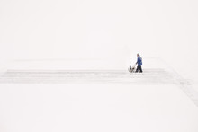 Man Pushing Snow Blower On Lake To Prepare An Ice Rink