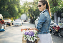Woman Carrying Wooden Basket Full Of  Spring Flowers