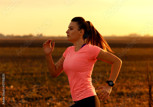 Zdjęcie XXL Sportowy kobieta bieg na wiejskiej drodze podczas zmierzchu.
