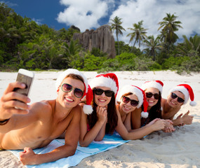 Canvas Print - group of friends in santa hats with taking selfie