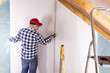 © artursfoto - Construction worker holding gypsum board. Attic renovation. Installation of drywall