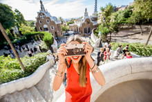 Woman Tourist In Red Dress Having Fun Visiting Famous Guell Park In Barcelona