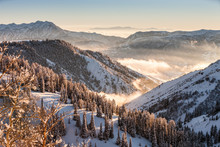 Snow Covered Rocky Mountains With Fog In Valleys At Sunset