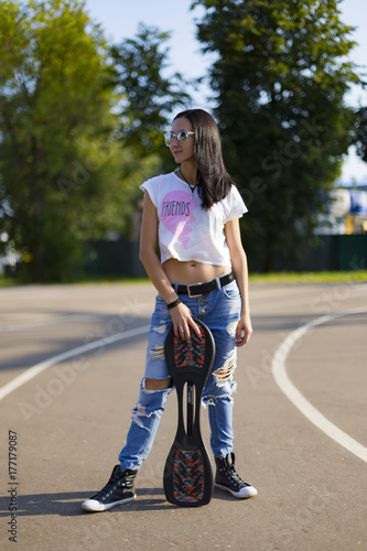 Zdjęcie XXL Lato, dziewczyna w parku jedzie na deskorolce