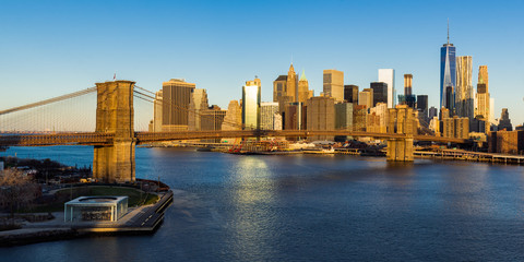 Fototapete - Sunrise on the Brooklyn Bridge, the East River and the skyscrapers of Lower Manhattan (panoramic). New York City