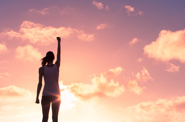 Girl power! Silhouette of strong victorious woman with her fist in the air. 