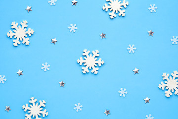 Wall Mural - A xmas card. Christmas pattern of small and large white snowflakes and with figurines of shiny stars on a blue background. Winter concept
