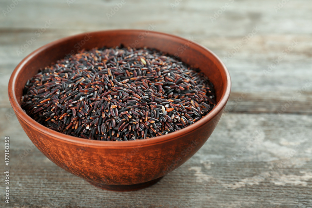 Bowl with raw rice on wooden table