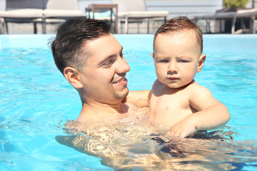 Poster - Child swimming lesson. Cute little boy learning to swim with father in pool