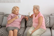 © Africa Studio - Elderly women drinking coffee while sitting on sofa at home
