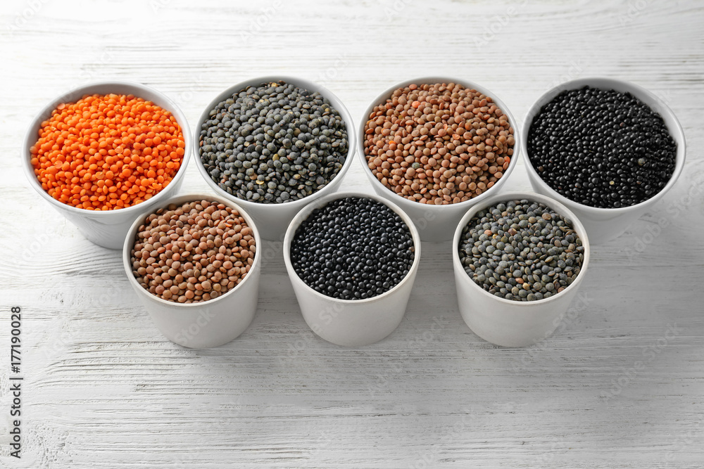 Bowls with different lentils on wooden table