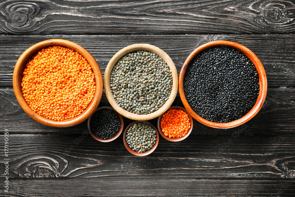 Bowls with different lentils on wooden table