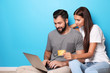 © Africa Studio - Young couple with laptop and credit card near color wall. Internet shopping concept
