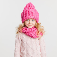 Winter Clothes. Portrait Of Little Curly Girl In Knitted Pink Winter Hat And Scarf