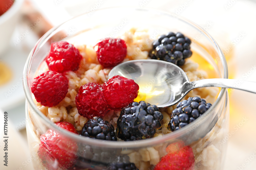 Tasty oatmeal with berries in jar on table, close up