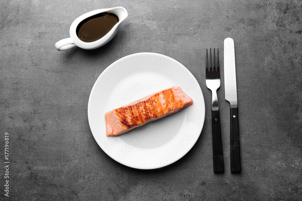 Plate with slice of delicious salmon on table