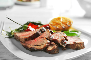 Poster - Plate with sliced delicious steak and vegetables on table