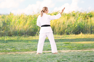 Wall Mural - Young woman practicing karate outdoors