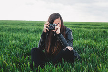 Girl Sitting On A Green Grass Taking Pictures
