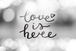 © redcollegiya - love is here lettering, vector handwritten text on blurred lights