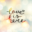 © redcollegiya - love is here lettering, vector handwritten text on blurred lights