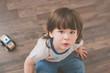 © Lea Csontos/Stocksy - Cute little boy sitting on a wooden floor looking up with a serious face.