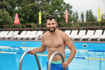 Wall Mural - Handsome young man getting out of swimming pool