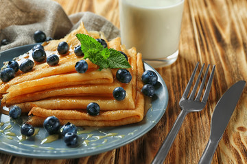 Canvas Print - Plate of tasty thin pancakes with blueberries on table